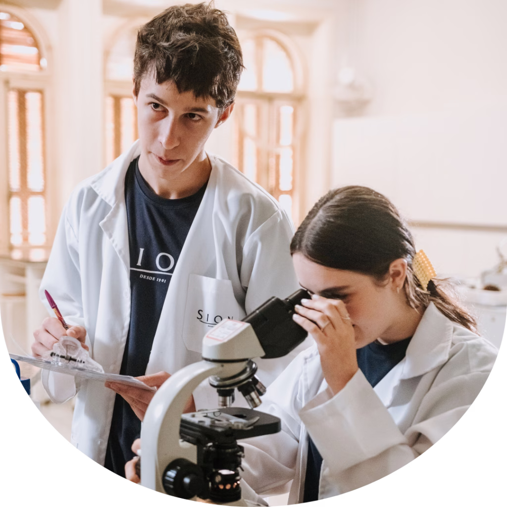 Estudantes do Ensino Médio do Colégio Sion Higienópolis realizando atividade de Ciências com microscópio em laboratório.