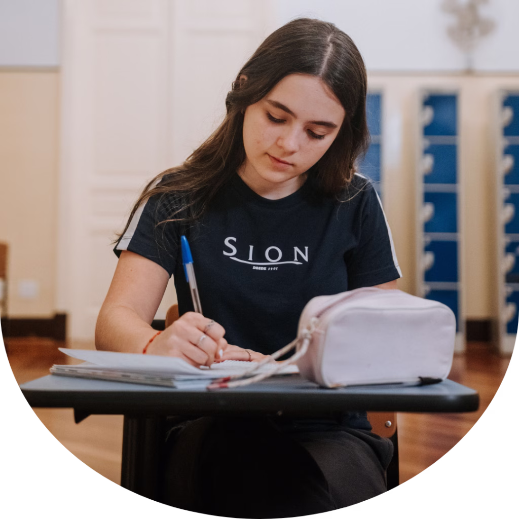 Estudante do Colégio Sion Higienópolis realizando atividade de estudo e escrita em sala de aula.