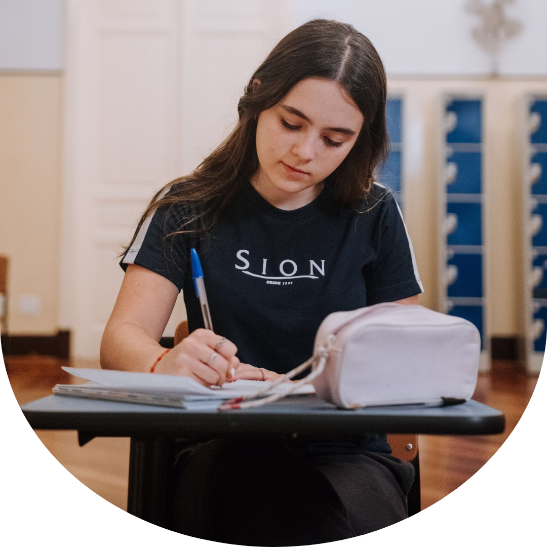 Estudante do Colégio Sion Higienópolis realizando atividade de estudo e escrita em sala de aula.